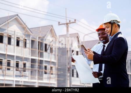 Un architecte asiatique et africain ingénieur deux plans d'équipe d'expertise avec un bâtiment en arrière-plan. Banque D'Images