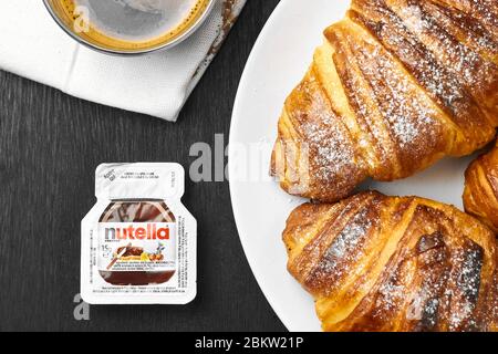 Croissants frais avec de la nutella et une tasse de café sur fond noir. Concept de petit déjeuner parfait. Pâtisserie maison. Banque D'Images