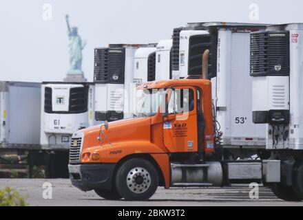 Brooklyn, États-Unis. 05e mai 2020. La Statue de la liberté se tient derrière des camions frigorifiques qui sont utilisés dans le cadre d'une morgue temporaire pour les victimes du coronavirus à New York le mardi 5 mai 2020. La pandémie du coronavirus COVID-19 touche 212 pays dans le monde, soit plus de 250,000 000 décès. Photo de John Angelillo/UPI crédit: UPI/Alay Live News Banque D'Images