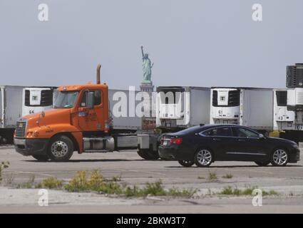 Brooklyn, États-Unis. 05e mai 2020. La Statue de la liberté se tient derrière des camions frigorifiques qui sont utilisés dans le cadre d'une morgue temporaire pour les victimes du coronavirus à New York le mardi 5 mai 2020. La pandémie du coronavirus COVID-19 touche 212 pays dans le monde, soit plus de 250,000 000 décès. Photo de John Angelillo/UPI crédit: UPI/Alay Live News Banque D'Images