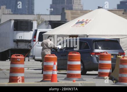 Brooklyn, États-Unis. 05e mai 2020. Un homme portant un masque facial prend les documents d'un conducteur de salon funéraire avant que la voiture ne soit autorisée à pénétrer dans une zone où des camions frigorifiques sont utilisés dans le cadre d'une morgue temporaire pour les victimes du coronavirus à New York le mardi 5 mai 2020. La pandémie du coronavirus COVID-19 touche 212 pays dans le monde, soit plus de 250,000 000 décès. Photo de John Angelillo/UPI crédit: UPI/Alay Live News Banque D'Images