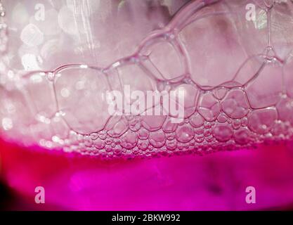 Liquide rose avec bulles de mousse sur la grenaille supérieure gros plan en format paysage Banque D'Images