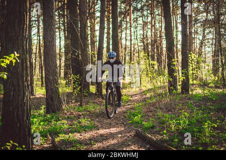 Un jeune homme fait du vélo tout-terrain dans la forêt. Jeune homme sportif qui fait du vélo dans le parc. Cycliste masculin portant un masque facial, avec filtre pm 2.5. Thème Banque D'Images
