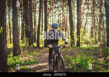 Sport. Cycliste sur une seule piste. Homme sur vélo portant un masque respiratoire avec filtre de protection à usage intensif. Masques respiratoires de sécurité Banque D'Images