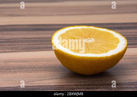 Gros plan de la moitié saine de citron jaune tourné vers le haut sur une table en bois Banque D'Images