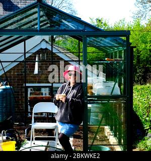 Femme appréciant le jardinage pendant la quarantaine verrouillage pandémie globale Covid-19 dans son propre jardin de chalet Banque D'Images