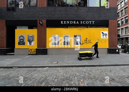 New York, États-Unis. 05e mai 2020. Un livreaute tire un chariot en passant devant un stor embarqué dans le quartier de Soho à New York, NY, le 5 mai 2020. Le quartier généralement animé et animé, bordé de boutiques de marque haut de gamme, est presque abandonné car les magasins restent fermés ou sont vacants en raison de l'impact économique de la pandémie COVID-19. (Anthony Behar/Sipa USA) crédit: SIPA USA/Alay Live News Banque D'Images