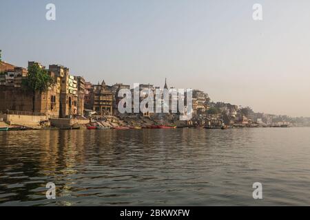 Vue depuis un bateau glisse à travers l'eau sur le fleuve Ganges le long de la rive de Varanasi, Inde. Banque D'Images
