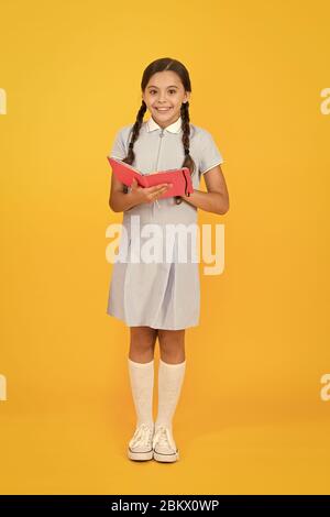 Souvenirs d'enfance. encyclopedia livre pour enfants. girl love littérature. vieille école. happy little girl en rétro vintage kid fashion. uniforme. retour à l'école. petite fille tenir cahier ou bloc-notes. Banque D'Images