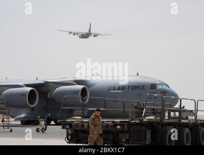 Un C-17 Globemaster III, déployé à partir de la 167e Escadre de transport aérien, Garde nationale aérienne de Virginie-Occidentale, est situé sur la ligne aérienne comme un C-130 au-dessus de la base aérienne Ali Al Salem, au Koweït, le 2 mai 2020. La 386e Escadre expéditionnaire aérienne est la porte d’entrée du Commandement Central des États-Unis et est responsable de fournir une puissance de combat décisive et un soutien théâtral inégalé. (ÉTATS-UNIS Photo de la Force aérienne par le premier Airman Isaiah J. Soliz) Banque D'Images