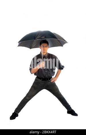 Photo d'un homme portant une chemise grise et un Jean noir avec un parapluie noir et posant avec des jambes plus longues sur fond blanc. Banque D'Images