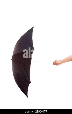 Prise de vue verticale d'une main tenant un parasol de couleur noire sur un fond blanc. Banque D'Images