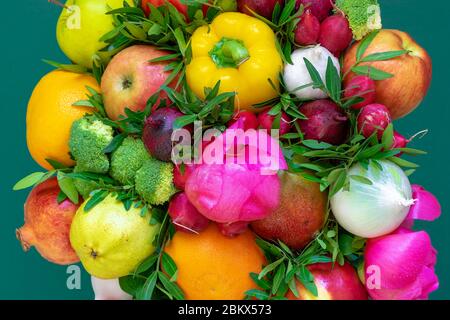 Merveilleux, non conventionnel, multicolore arrangement floristique avec des fruits, des légumes, des pivoines et des feuilles sur un fond vert. Gros plan, vue de dessus Banque D'Images