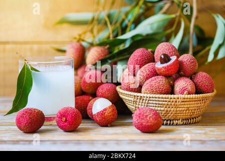 Jus de litchi sur table en bois / boisson fraîche de litchi et tranche épluchée avec des feuilles vertes récolte dans le panier de fruits tropicaux d'arbre été en Thaïlande Banque D'Images