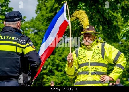 Un manifestant portant un drapeau hollandais fait face à un policier anti-émeute pendant la manifestation.des dizaines d'activistes anti-verrouillage ont été arrêtés alors qu'ils manifestaient contre les mesures contre le virus corona à la Haye. Banque D'Images