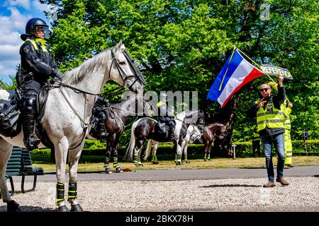 Un manifestant a agité le drapeau hollandais alors que la police anti-émeute regarde pendant la manifestation.des dizaines d'activistes anti-verrouillage ont été arrêtés alors qu'ils manifestaient contre les mesures contre le virus corona à la Haye. Banque D'Images