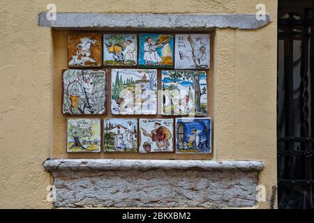 Carreaux de céramique peints à la main par Sergio Vellini consacrés à la vie des frères sur un mur dans le centre historique de Bardolino, Vérone, Vénétie, Italie Banque D'Images