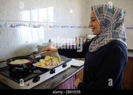 Gaza. 4 mai 2020. Hanady Tawahin, cuisine dans la cuisine de Deir al-Balah, dans le centre de la bande de Gaza, 4 mai 2020. Dans la cuisine de sa maison dans la ville centrale de la bande de Gaza, Deir al-Balah, Hanady Tawahin prépare chaque jour différents types de nourriture et de desserts pour les clients. Cette femme de 31 ans a utilisé son talent pour cuisiner des plats palestiniens traditionnels pour gagner de l'argent pendant le Saint mois de jeûne du Ramadan. POUR ALLER AVEC: 'Feature: Les femmes palestiniennes cuisent pour gagner de l'argent pour la vie pendant le Ramadan' crédit: Rizek Abdeljawad/Xinhua/Alamy Live News Banque D'Images