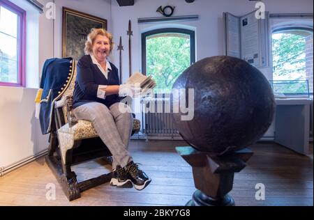 Bodenwerder, Allemagne. 04e mai 2020. La directrice du musée Claudia Erler est assise au Musée Münchaussen de Bodenwerder avec un livre historique. En tant que personnage littéraire ou héros de cinéma, le "mensonge baron" Münchhausen, qui roule sur un canon, est connu dans le monde entier. Le personnage artistique est basé sur la personnalité historique Hieronymus Carl Friedrich Baron von Münchhausen, né il y a 300 ans le 11 mai 1720 à Bodenwerder sur le Weser. Le célèbre Baron de Münchhausen est commémoré. Crédit : Julian Strattischulte/dpa/Alay Live News Banque D'Images