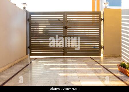 Portes d'entrée en métal gris dans une clôture en brique avec serrure. Banque D'Images