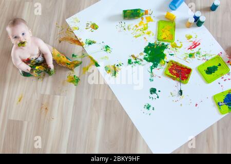 Bébé enfant tire avec des peintures colorées mains, pieds sales. Liste blanche. Banque D'Images