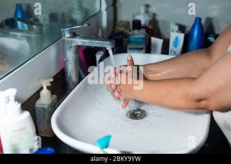 Un adulte se lavant correctement les mains et les bras avec du savon à l'alcool sous l'évier/lavabo des toilettes pour combattre le coronavirus. Banque D'Images