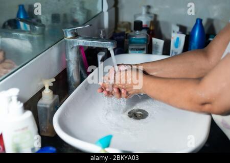 Un adulte se lavant correctement les mains et les bras avec du savon à l'alcool sous l'évier/lavabo des toilettes pour combattre le coronavirus. Banque D'Images