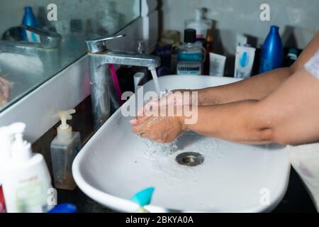 Un adulte se lavant correctement les mains et les bras avec du savon à l'alcool sous l'évier/lavabo des toilettes pour combattre le coronavirus. Banque D'Images