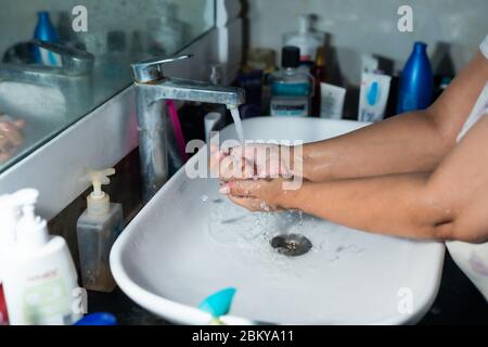 Un adulte se lavant correctement les mains et les bras avec du savon à l'alcool sous l'évier/lavabo des toilettes pour combattre le coronavirus. Banque D'Images