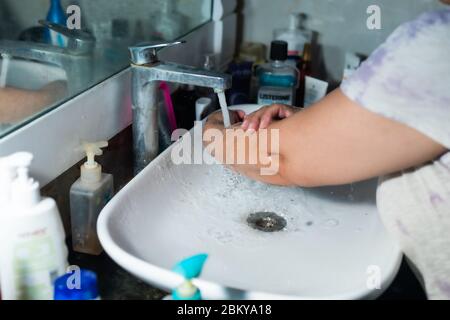 Un adulte se lavant correctement les mains et les bras avec du savon à l'alcool sous l'évier/lavabo des toilettes pour combattre le coronavirus. Banque D'Images