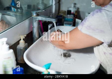 Un adulte se lavant correctement les mains et les bras avec du savon à l'alcool sous l'évier/lavabo des toilettes pour combattre le coronavirus. Banque D'Images