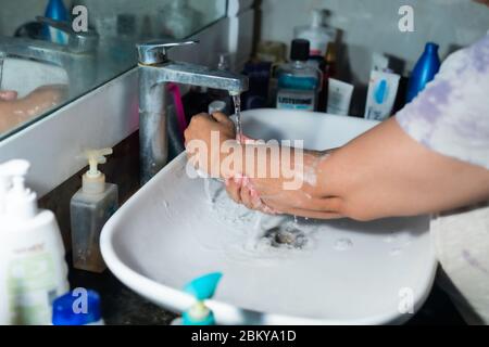 Un adulte se lavant correctement les mains et les bras avec du savon à l'alcool sous l'évier/lavabo des toilettes pour combattre le coronavirus. Banque D'Images