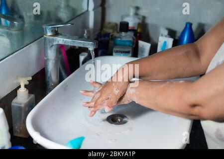 Un adulte se lavant correctement les mains et les bras avec du savon à l'alcool sous l'évier/lavabo des toilettes pour combattre le coronavirus. Banque D'Images