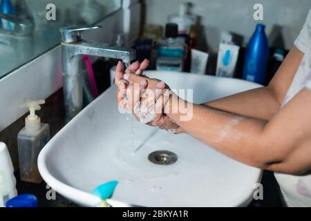 Un adulte se lavant correctement les mains et les bras avec du savon à l'alcool sous l'évier/lavabo des toilettes pour combattre le coronavirus. Banque D'Images