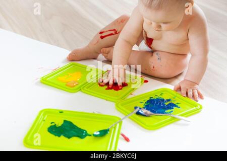 Bébé enfant tire avec des peintures colorées mains, pieds sales. Liste blanche. Banque D'Images