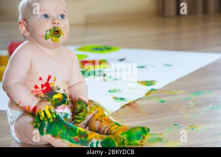 Bébé enfant tire avec des peintures colorées mains, pieds sales. Liste blanche. Banque D'Images