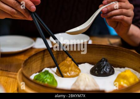 Une dame chinoise ramasse une soupe de xiaolongbao gourmet au foie gras en utilisant des baguettes et une cuillère. Banque D'Images