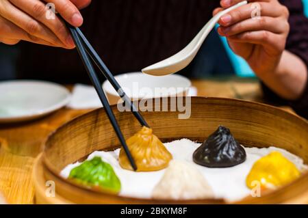 Une dame chinoise ramasse une soupe de xiaolongbao gourmet au foie gras en utilisant des baguettes et une cuillère. Banque D'Images