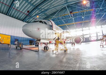 Vue panoramique sur les hangars et les avions en entretien, avec des lumières lumineuses à l'extérieur de la porte Banque D'Images