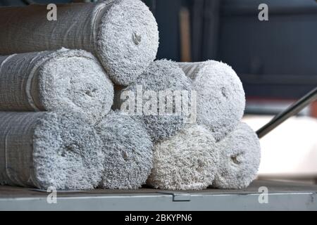 Des rouleaux de tissu blanc non tissé se trouvent sur les étagères du rack de l'entrepôt Banque D'Images