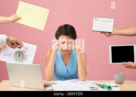 Surchargés de jeune employé refuse toutes choses, s'affronter dans l'ennui, s'assoit sur le bureau avec les documents sur papier et le bloc-notes, isolated over pink backgroun Banque D'Images