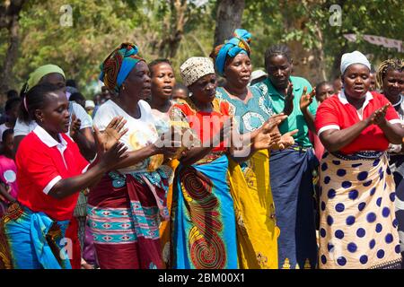 Femmes dansant et chantant vêtues de tissus africains traditionnels colorés connus sous le nom de capulana au Mozambique Banque D'Images