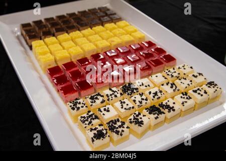 Gros plan sur un plateau blanc de mini-tranches de gâteaux colorés aux saveurs nombreuses Banque D'Images