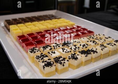 Mini-tranche de gâteaux colorés avec beaucoup de saveurs sur un plateau blanc.petits gâteaux en-cas dans un buffet de fête. Banque D'Images