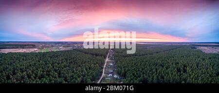 Vue depuis le dessus de la campagne et de la forêt de pins en soirée. Magnifique ciel au coucher du soleil Banque D'Images