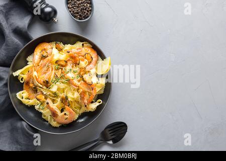 Pâtes mafaldine ou réginelle avec fruits de mer, crevettes, assiette noire de moules sur table grise, vue d'en haut. Copier l'espace. Banque D'Images