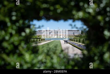 06 mai 2020, Bade-Wurtemberg, Ludwigsburg: Les visiteurs du salon de jardin 'Blühendes Barock' se tiennent à côté d'un lit de fleurs, en arrière-plan le palais résidentiel meublé peut être vu. Au cours de la détente des restrictions du coronavirus, les jardins du baroque en fleurs ont également été partiellement rouverts au public. Photo: Marijan Murat/dpa Banque D'Images