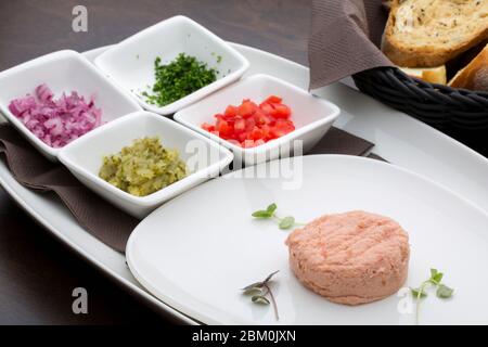 Un pate de thon avec tomates, concombres, oignons et persil dans des assiettes en céramique blanche avec du pain maison en arrière-plan Banque D'Images