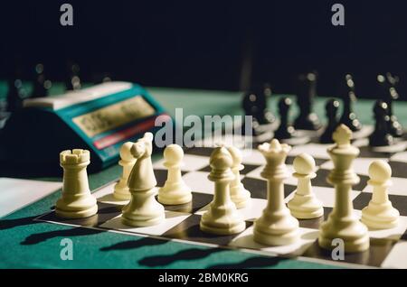 Échiquier de tournoi avec table verte, pièces blanches prêtes pour le début du jeu et fond noir. Le blanc doit d'abord bouger Banque D'Images