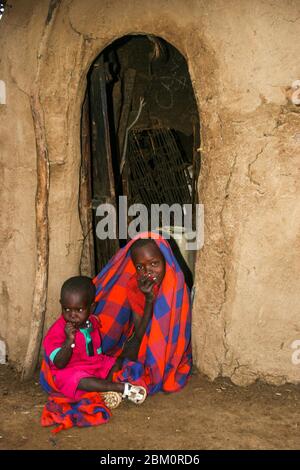 Jeune enfant de Maasai à l'entrée d'une hutte. Maasai est un groupe ethnique de personnes semi-nomades photographiées au Kenya Banque D'Images